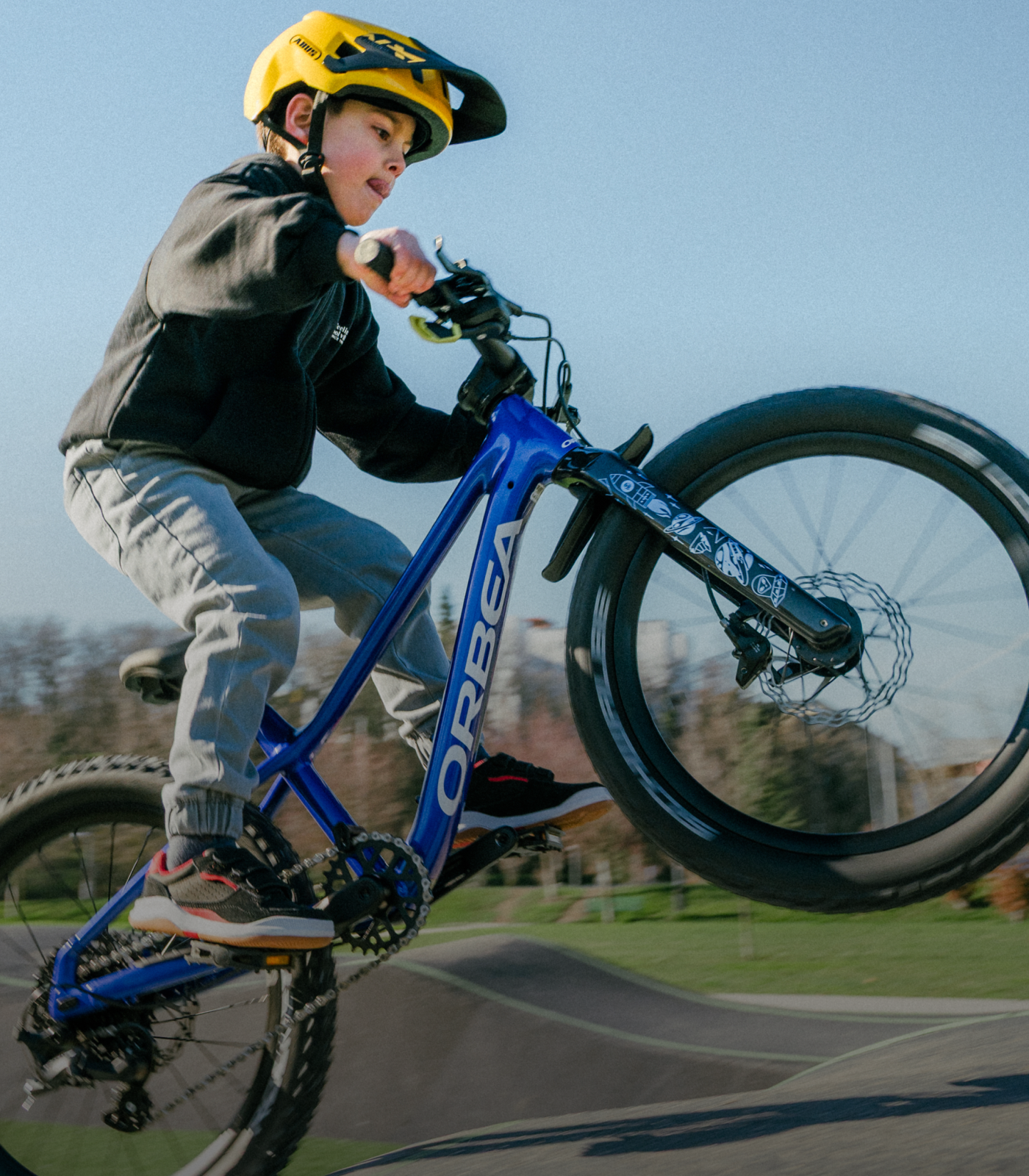 Un jeune garçon fait du VTT sur une piste de vélo dans un parc, avec son VTT Kimu de la marque Orbea